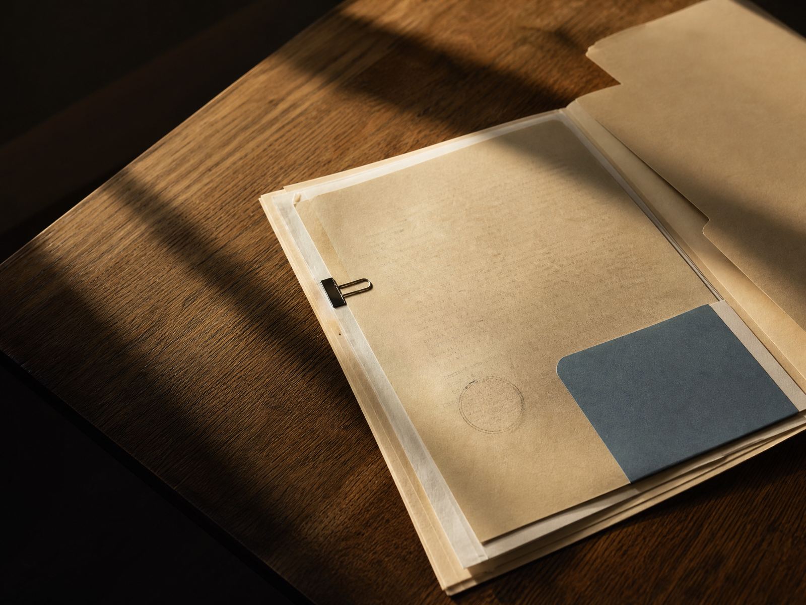 An archival folder and record materials on a sunlit document table.